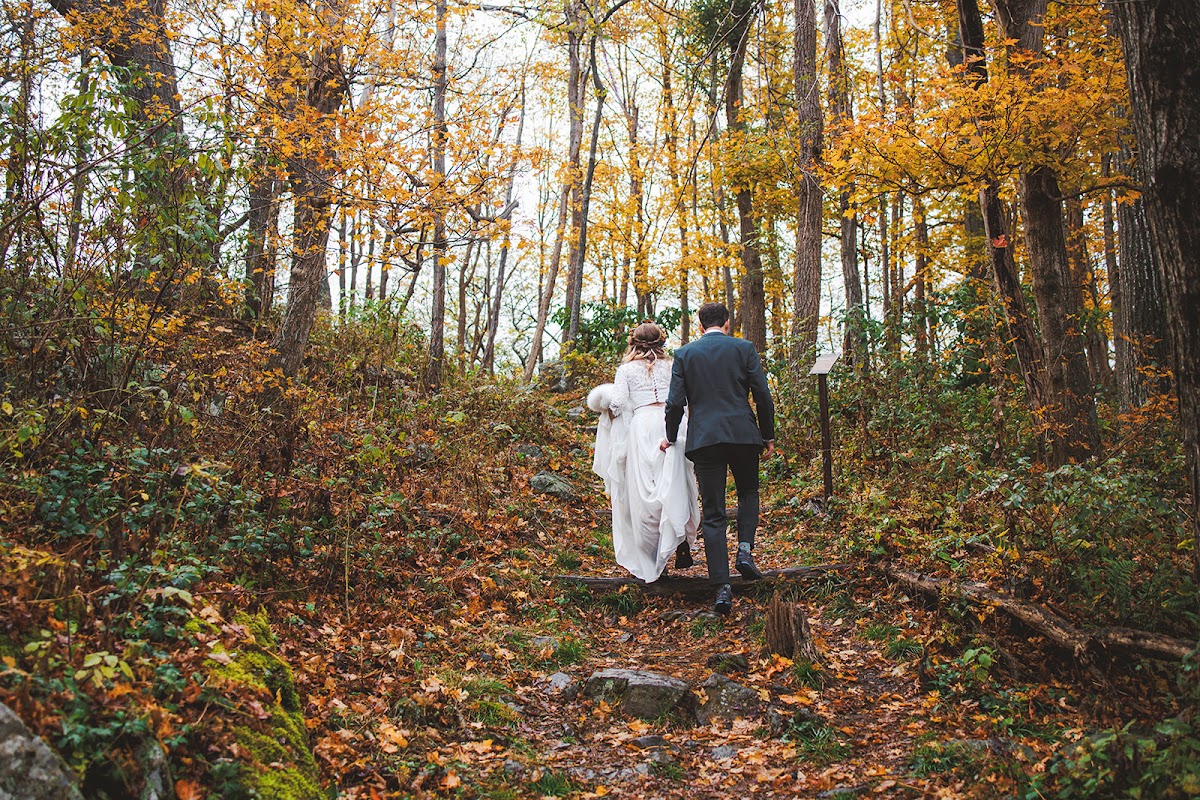 Sara and Ryan walking away up a leaf-covered forest trail in Shenandoah National Park, surrounded by yellow autumn foliage