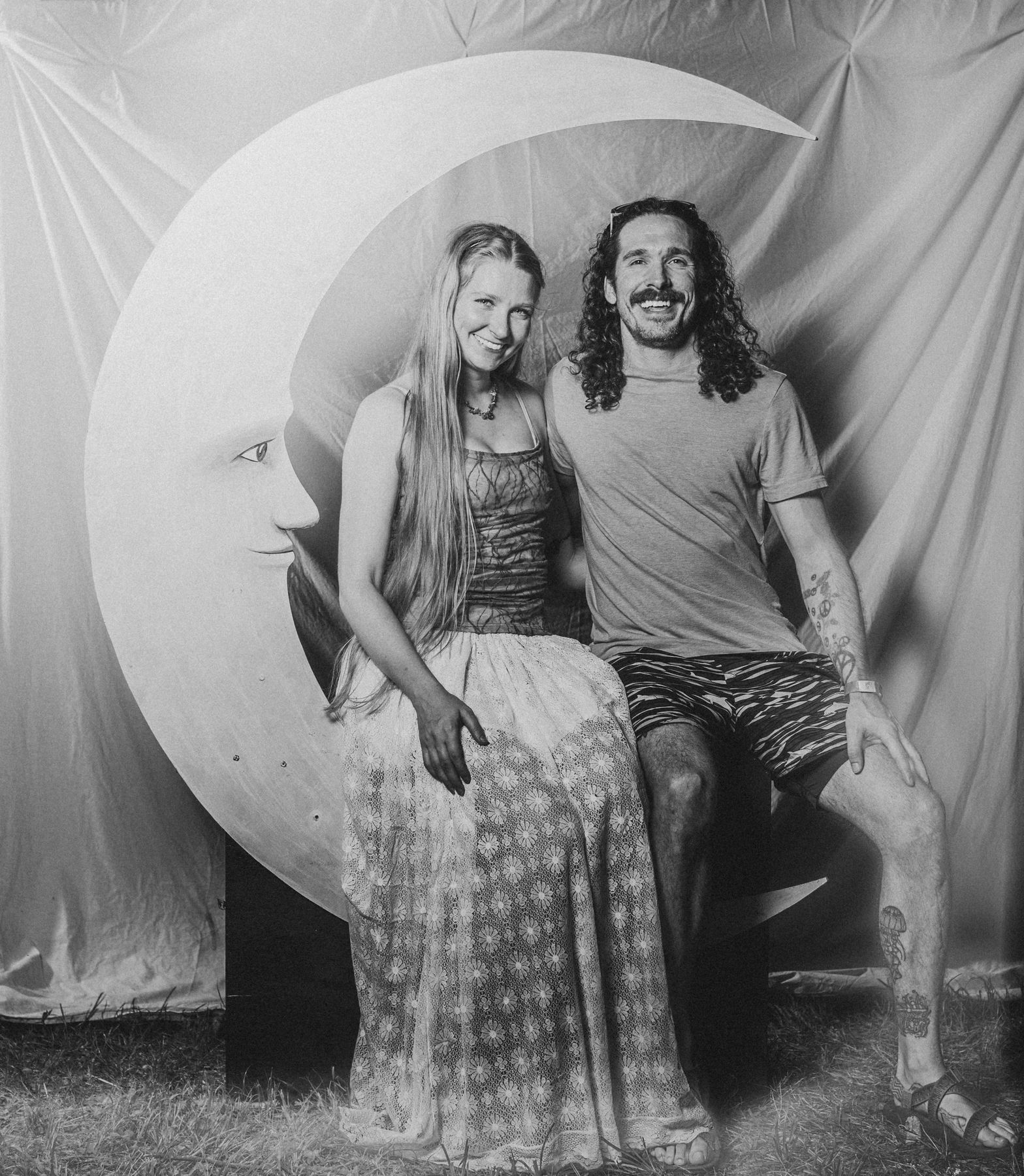 A couple seated side by side on the crescent moon, her long hair falling past her waist, in black and white