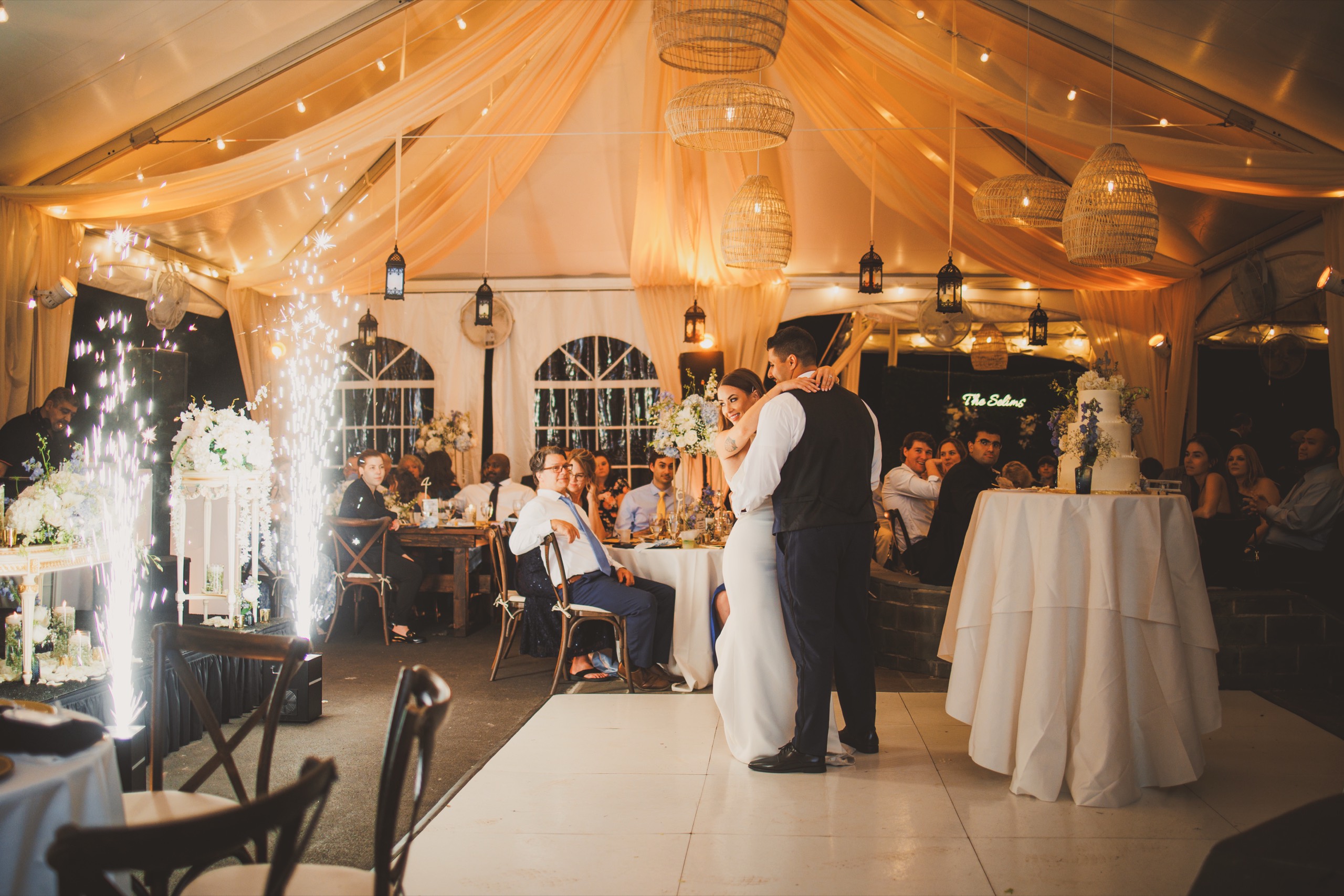 Bailey and Youssef's first dance under a draped tent as sparkler fountains light the room